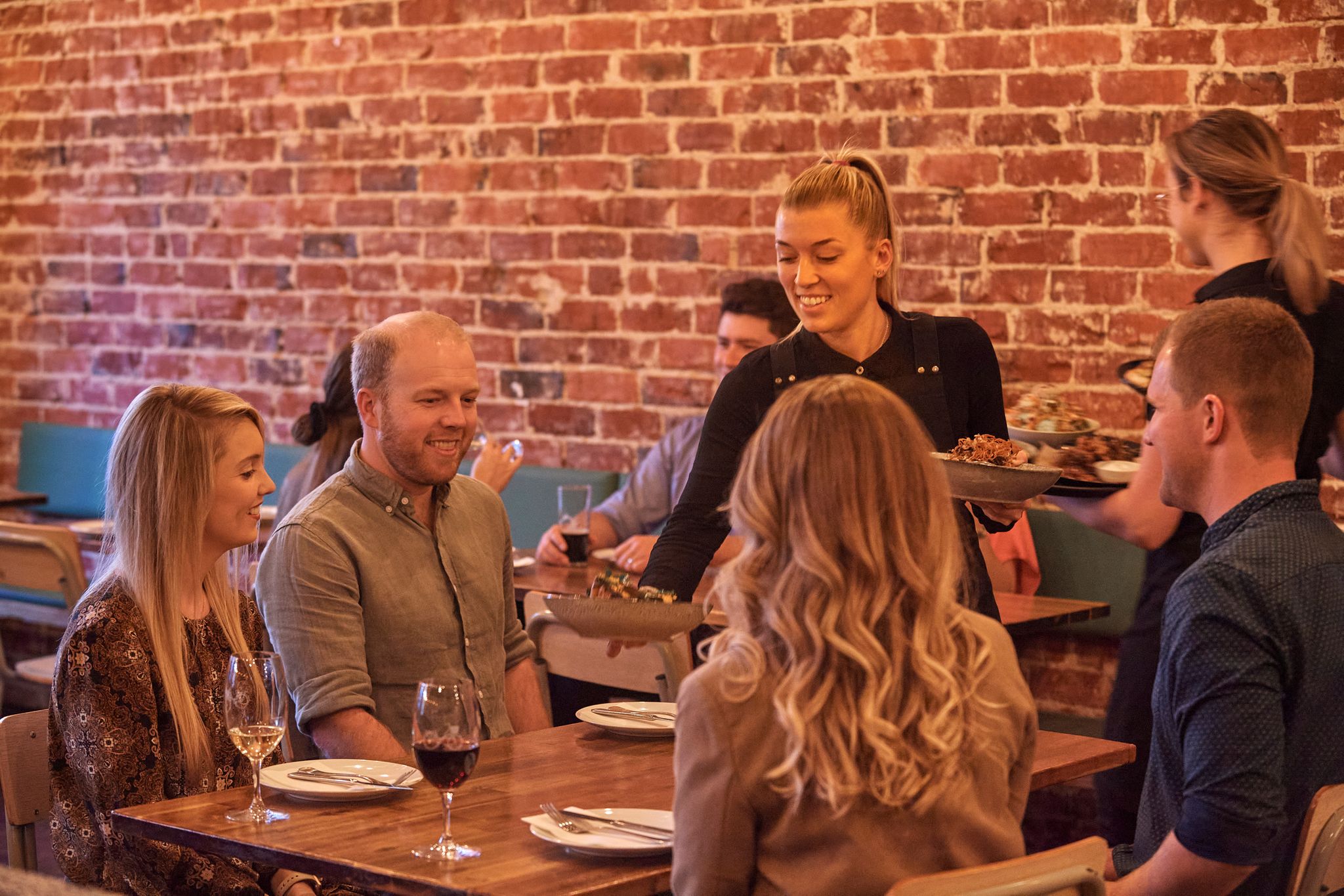 A group of people are served gourmet food and wine at Market Eating House