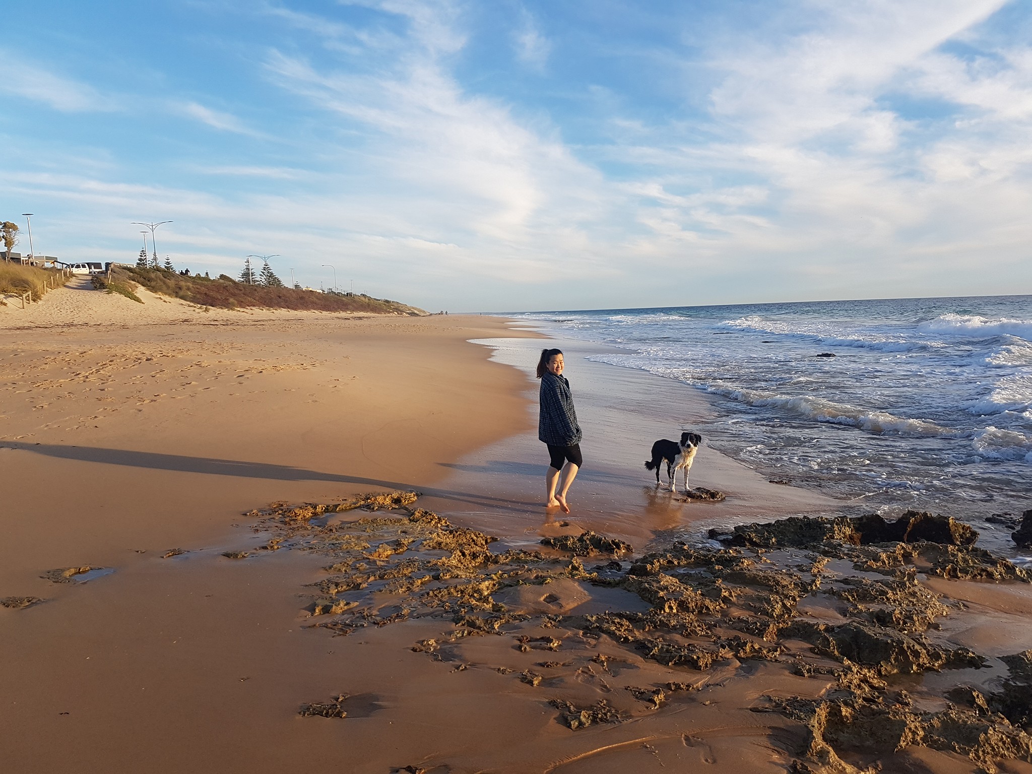 A woman walks her dog on a beach