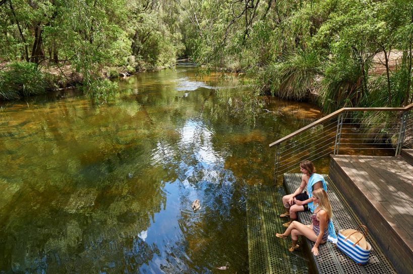 2 people sitting on the stairs in front of a freshwater pool