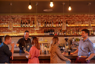 2 couples at a bar drinking wine