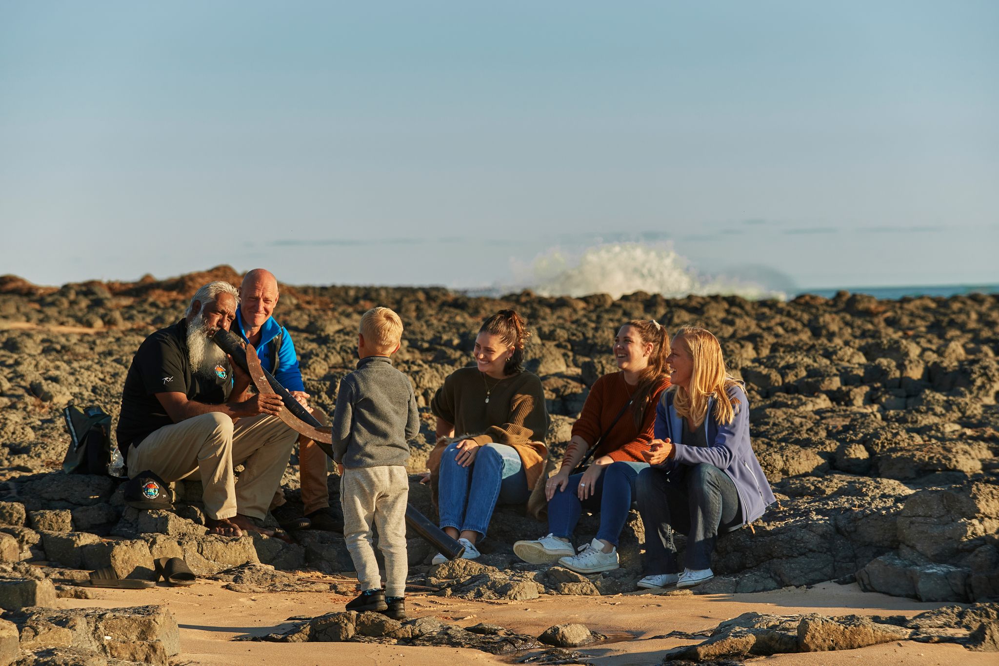 A group of people on a beach with a didgeridoo