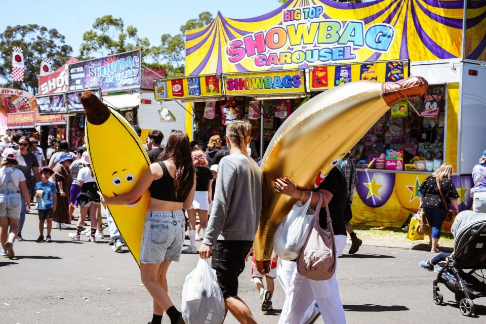 2 people carrying giant banana toys walking in a festival