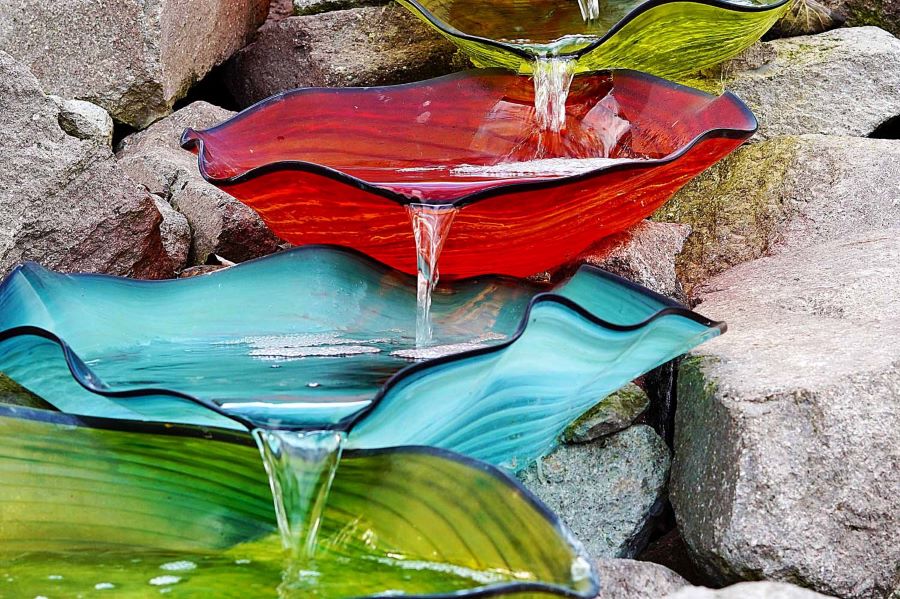 Water cascading down a red bowl onto a blue bowl onto a green bowl